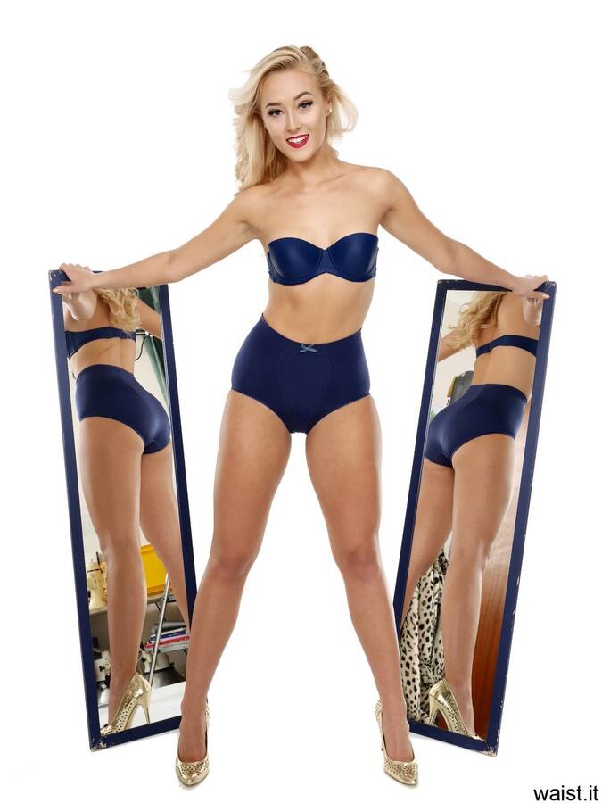 photographer waist it vintage modelling photo. model not on mcm poses in vintagestyle blue strapless bra and matching nylonlycra pantie girdle worn as hotpants she poses with a pair of blueframed 120cm mirrors  carefully angled to give a good allround view her