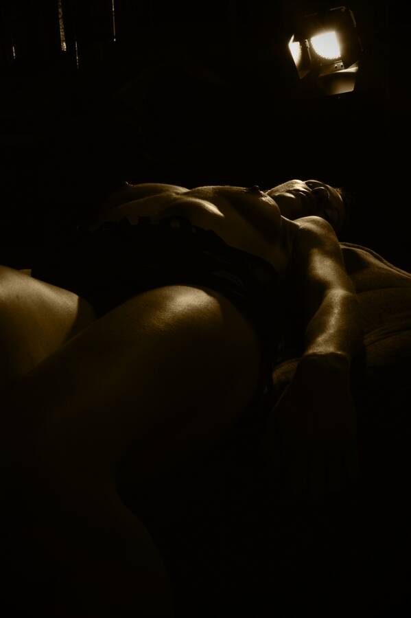 photographer Alan Tog nude modelling photo. model lying back waiting for the action to start movie set type scenario light with barn doors in the image deliberately.